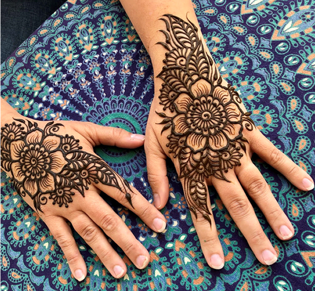 Two hands with henna designs on blue fabric